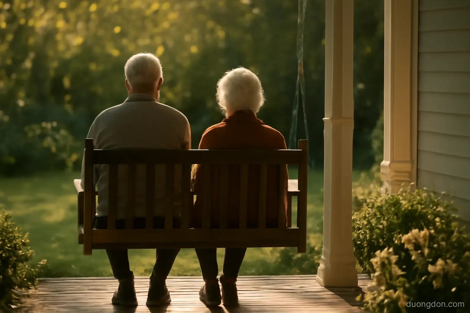 an elderly couple sitting on a porch bench in the afternoon sun seen from a distance, quiet garden, faces not detailed